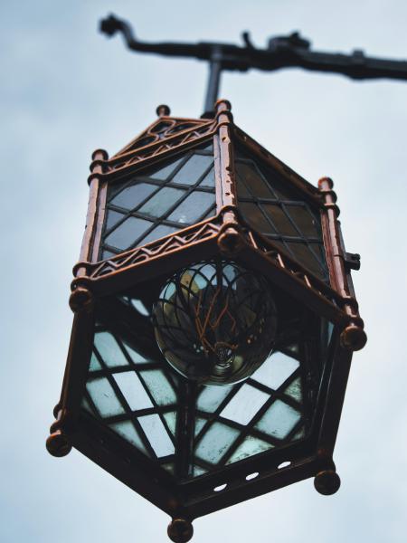 Ornate vintage lantern hanging against a cloudy sky