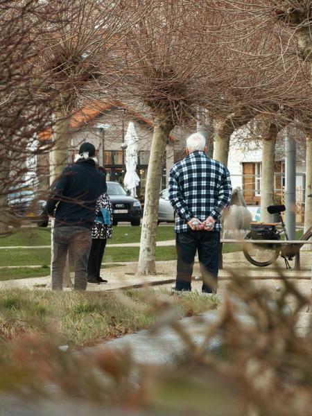 Two people stand in a park with bare trees