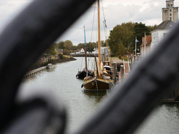 Sailboats docked along a canal with buildings and trees